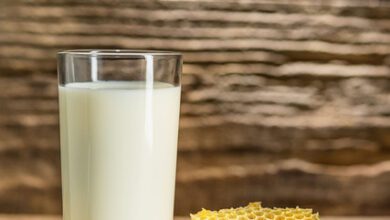 Favo de mel e copo de leite na mesa de madeira